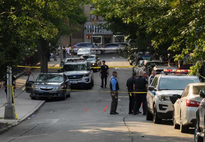 shutterstock_2330301305-7 Police officers secure a residential street with patrol cars and yellow tape