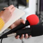 Jewish Republican Donors Amid Growing Disputes Over Israel Policy Journalist holding two microphones while writing in a notebook