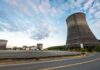 IAEA Warns After Drone Hits Kursk Nuclear Site Cooling towers at an industrial power plant under a partly cloudy sky