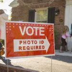 Armed Agents: ICE Faces Legal Setbacks on Two Fronts Red voting sign with arrow near people entering a polling place