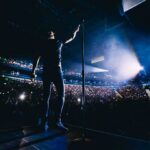 Onstage Killing: Live Show Sparks Fury Singer on stage facing a large concert crowd