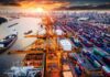 Container port with cranes and cargo ships at sunset
