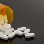 Prescription bottle with white tablets spilling out