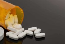 Prescription bottle with white tablets spilling out