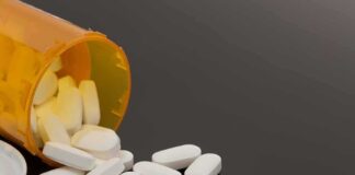 Prescription bottle with white tablets spilling out