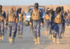 New Video Escalates Sinaloa Faction Feud Camouflaged soldiers wearing masks and vests walk in desert.
