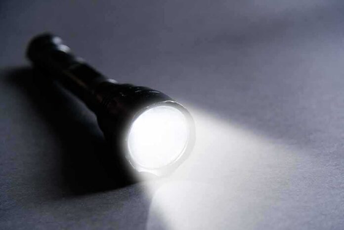 shutterstock_1048735250 Flashlight shining a bright beam on a dark surface
