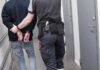 Man Hospitalized After Targeted ICE Arrest Security officer escorts handcuffed person down hallway