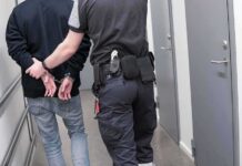 Man Hospitalized After Targeted ICE Arrest Security officer escorts handcuffed person down hallway