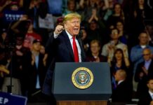 Donald Trump speaking at a rally behind a presidential podium