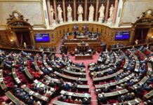 Warnings, Wartime Orders and Funding Under Debate Parliament chamber with lawmakers seated in semicircular rows