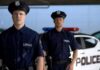 Two police officers standing near a patrol car