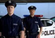U.S. Marine Arrested After Woman Killed in Okinawa Two police officers standing near a patrol car