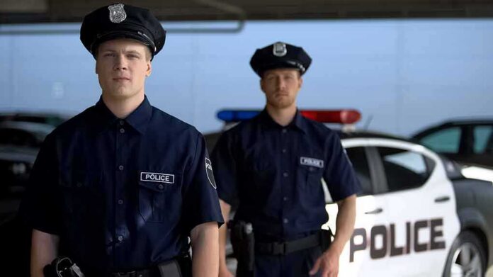 Two police officers standing near a patrol car