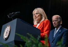 Jill Biden speaks at a podium as Joe Biden stands behind her