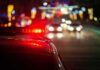 Truck Driver Lawsuit Nears End Police car with flashing red lights on a city street at night