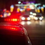 Truck Driver Lawsuit Nears End Police car with flashing red lights on a city street at night