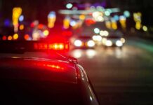 Truck Driver Lawsuit Nears End Police car with flashing red lights on a city street at night