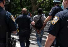 Police escort a handcuffed man across a city street