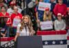 Trump Praises Supporter Who Struck Protester Walter Jones speaks at a rally podium with a crowd and flags in the background