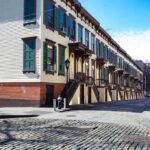 Mother Reports Man Harassing Children Near Storm Drain Row houses along a cobblestone street in an urban setting