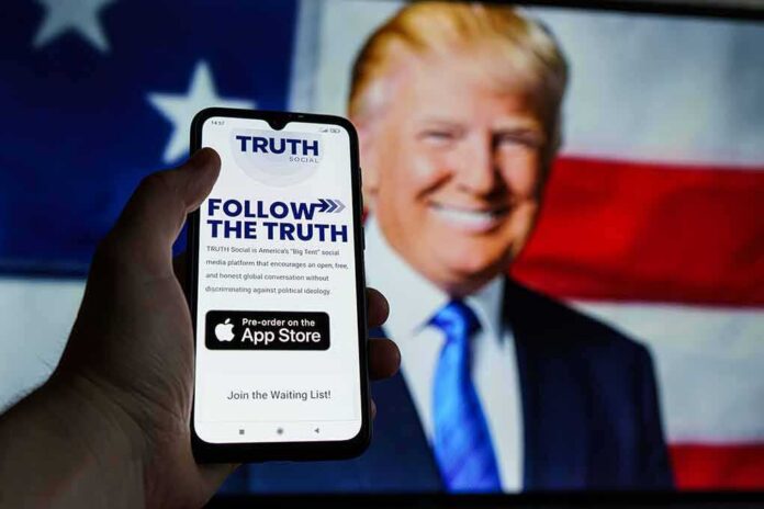 shutterstock_2068203671 Smartphone showing Truth Social app screen with Donald Trump on a U.S. flag backdrop