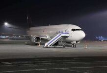 Passenger airplane parked on tarmac at night with mobile stairs